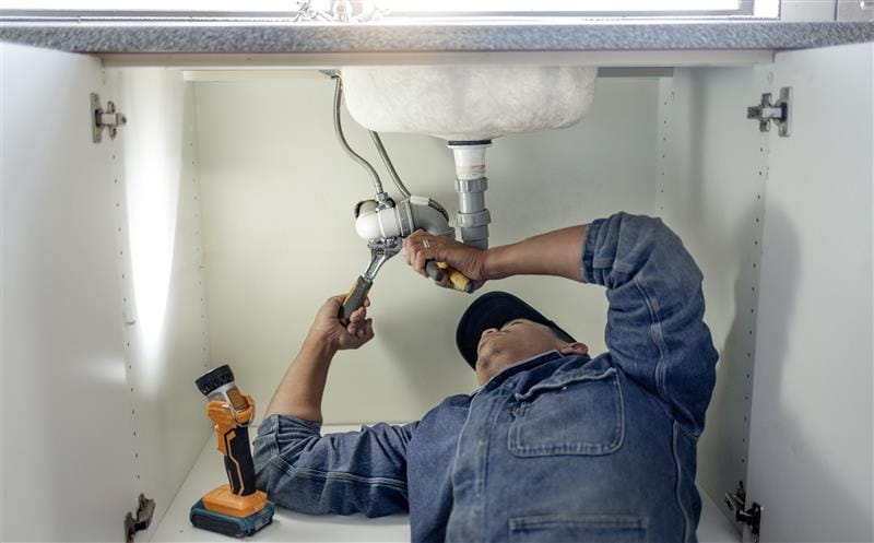 Plumber repairing pipes beneath a bathroom sink in Clearwater
