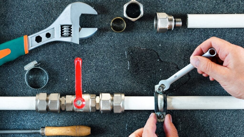 Plumber repairing a pipe valve with an adjustable wrench in Clearwater