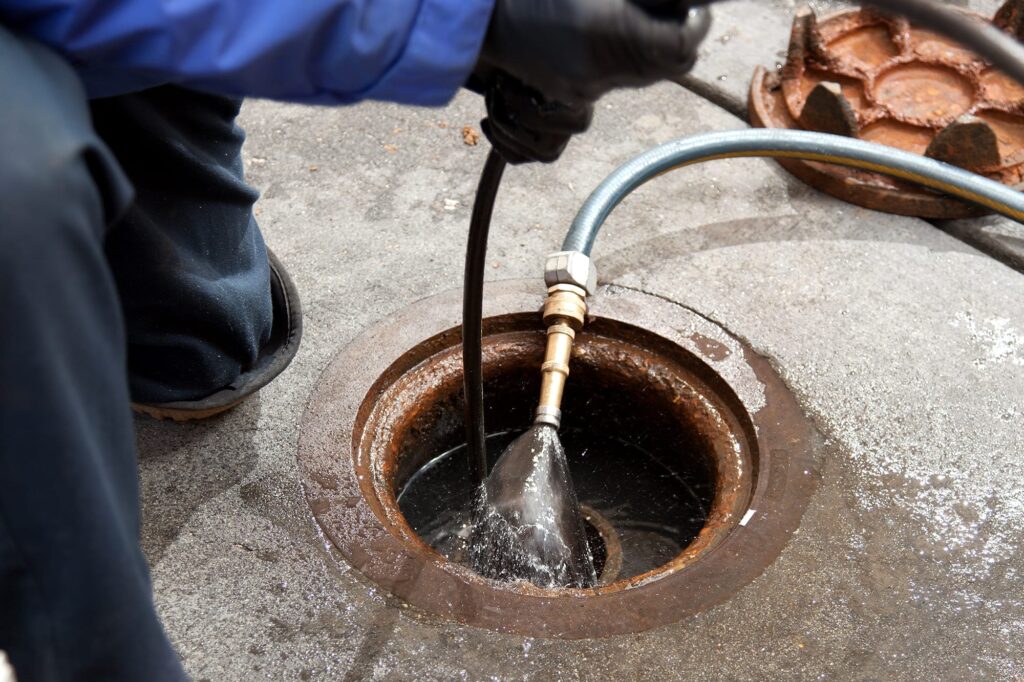 Plumber hydro jetting a sewer line through a manhole in Clearwater