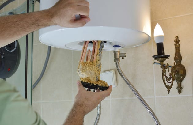 Technician removing mineral buildup from a water heater in Clearwater