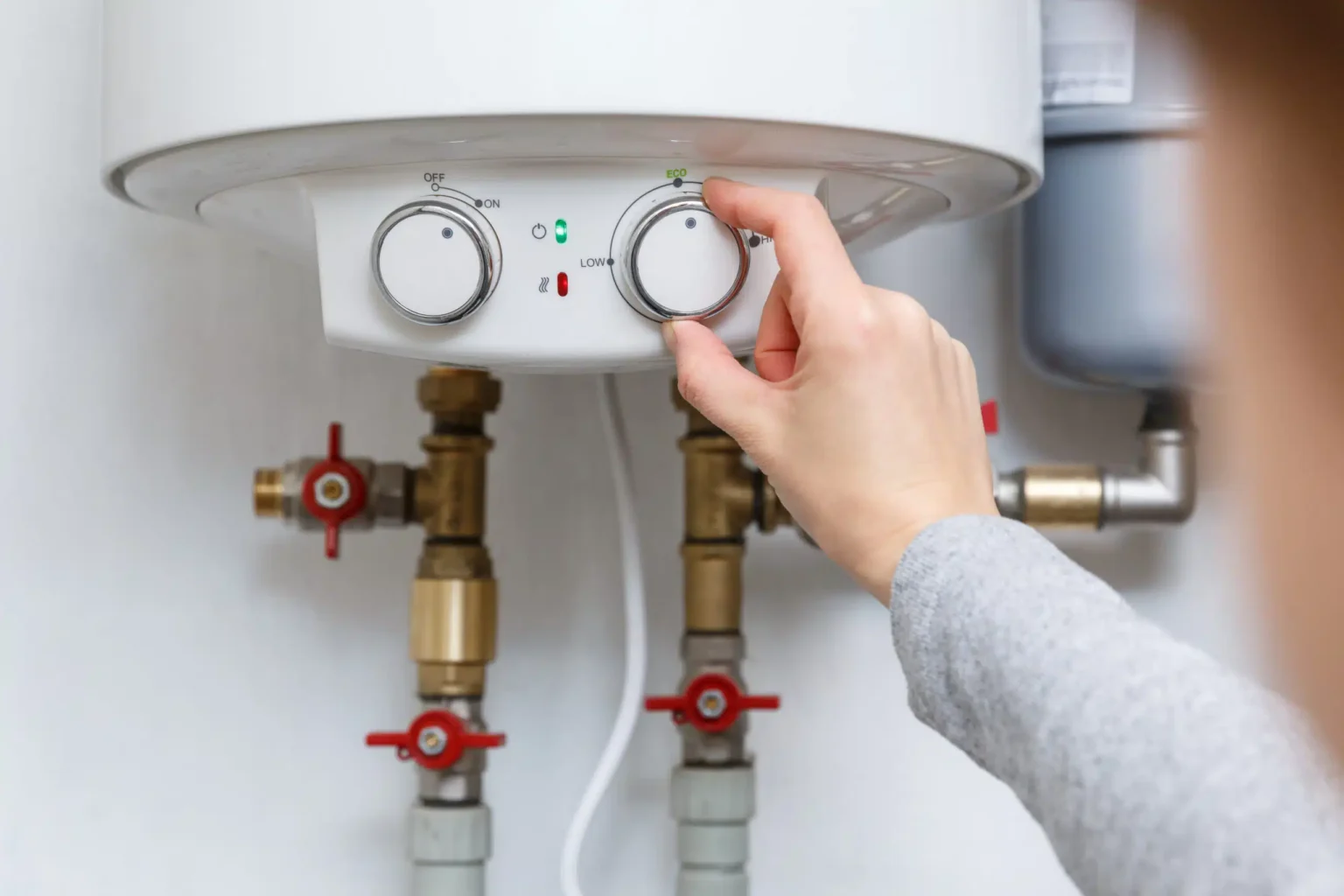 Homeowner adjusting the temperature controls on a water heater in Clearwater